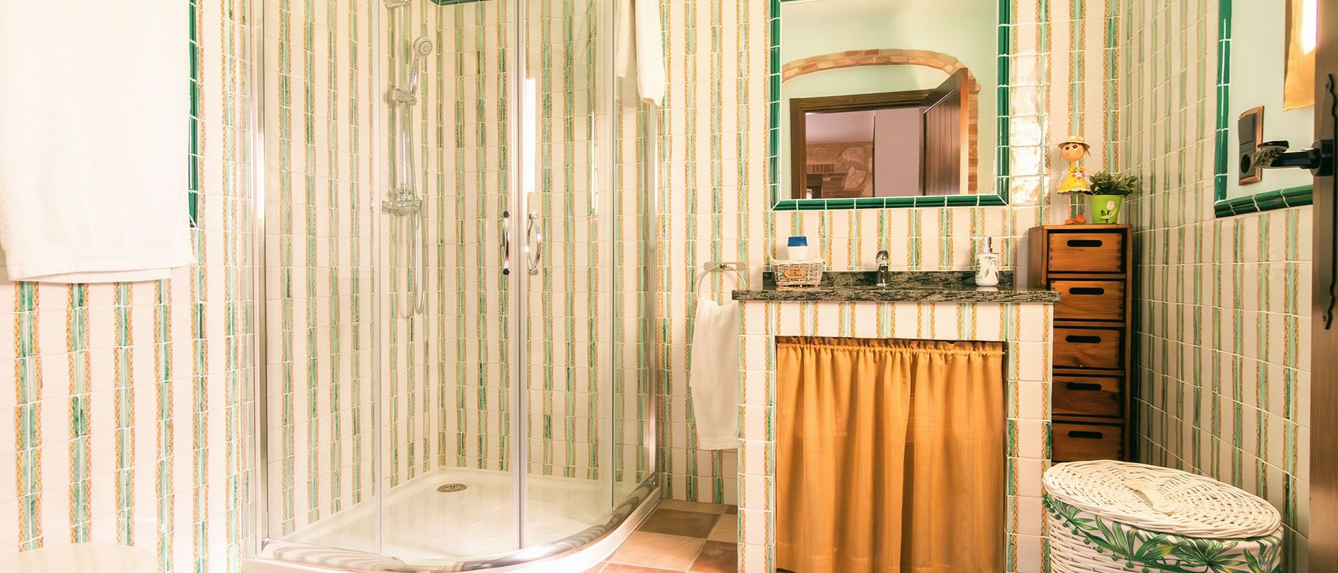 Baño con ducha acristalada, mueble de obra y azulejo de rayas