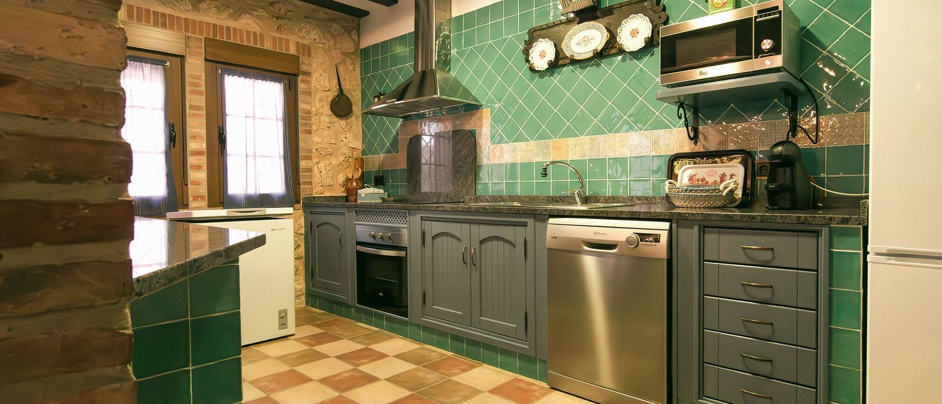 Cocina equipada de azulejo verde con horno, lavavajillas y campana