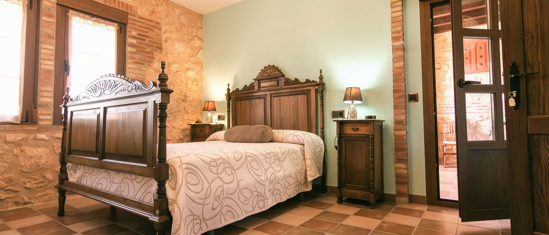 Dormitorio con cama de madera tallada y suelo de barro