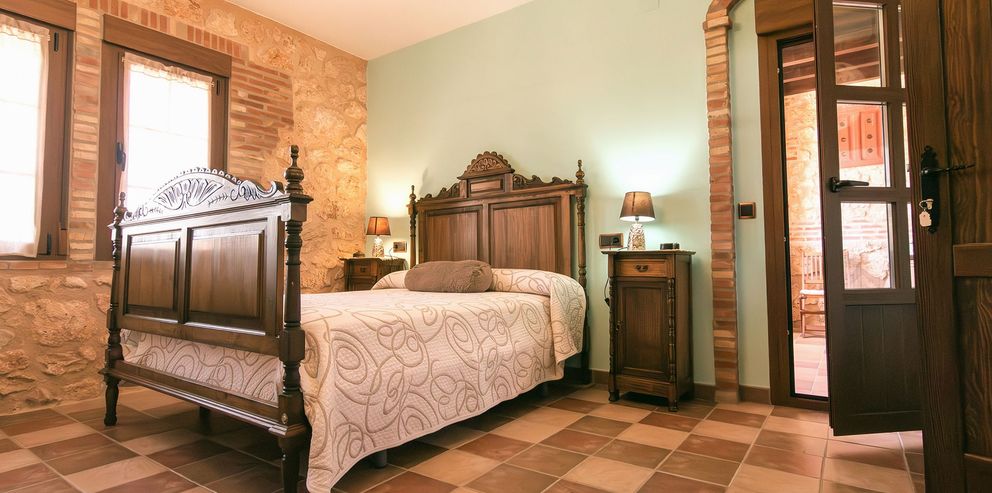 Dormitorio con cama de madera tallada y suelo de barro