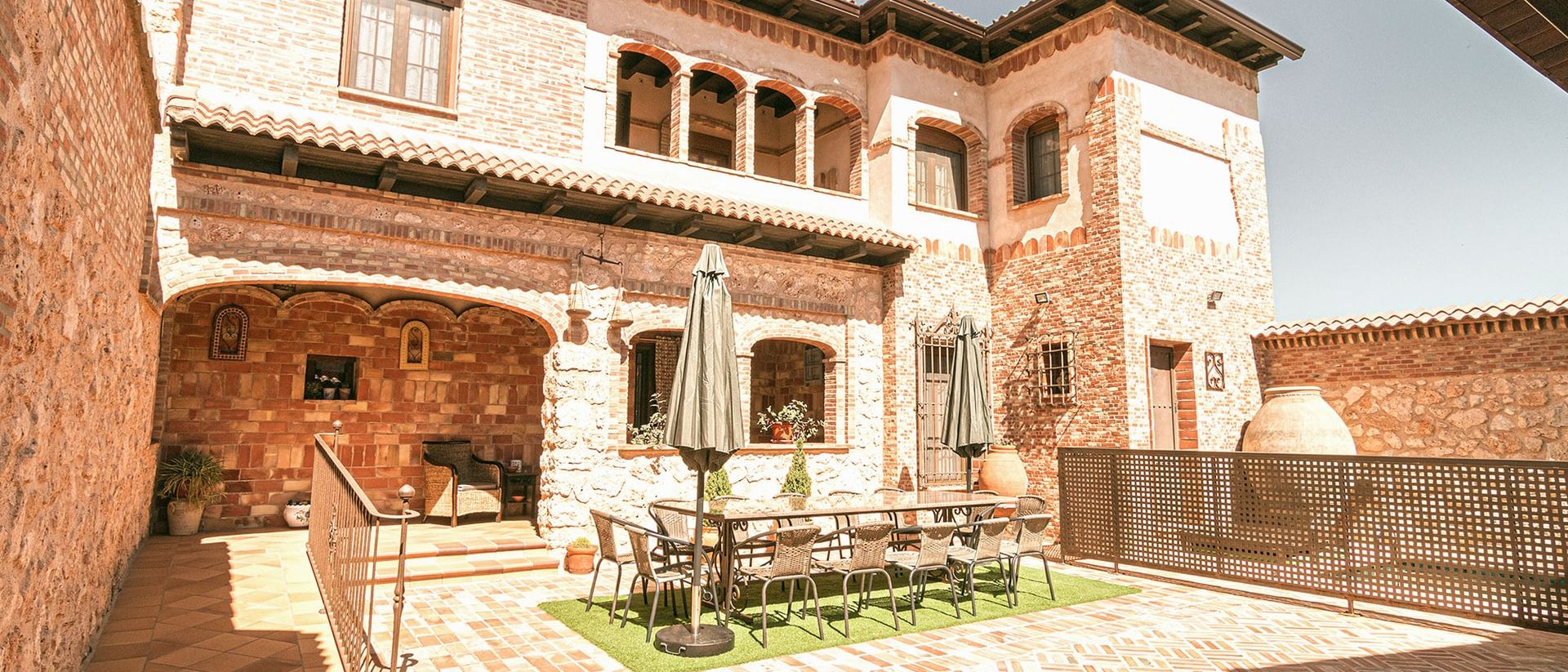 Patio de la casa con la mesa de exterior ante la fachada de tres plantas