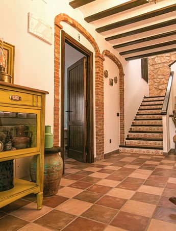 Recibidor con un aparador amarillo, una mecedora y la escalera al fondo